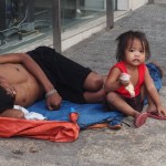 A man in downtown Cebu sleeps on the street with his young child