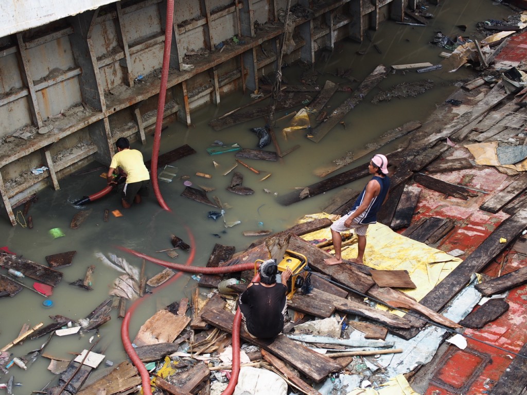 A salvage crew drains the water from inside a large ship that was blown ashore by super typhoon Yolanda