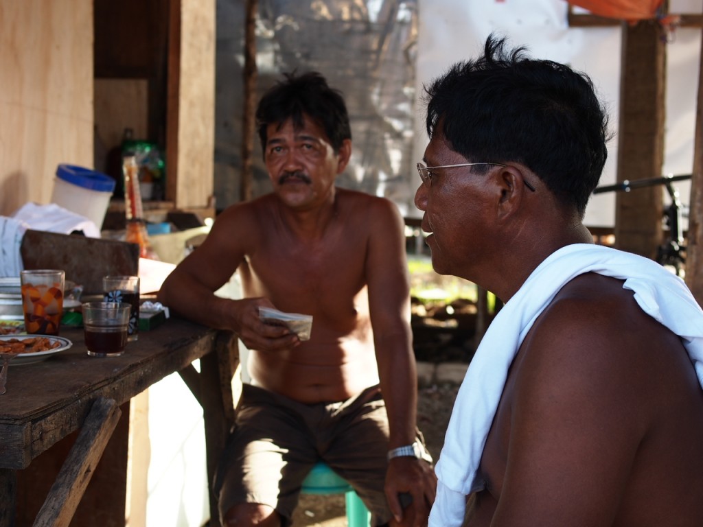 Two men enjoy an afternoon glass of tuba while taking a break from rebuilding their homes