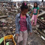 Two teenage girls help clear the rubble from their destroyed home